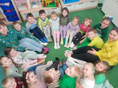 Grupa dzieci i 2 panie pozujący do zdjęcia w kolorowych skarpetkach. Wewnątrz.