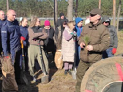 Grupa osób słucha instruktażu. Na zewnątrz.