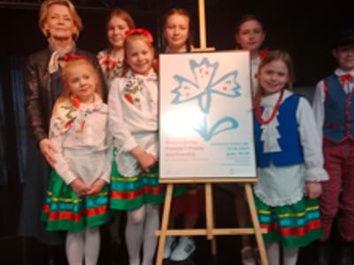 Grupa dzieci i pani pozujący do zdjęcia. Wewnątrz.