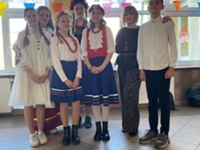 Grupa dzieci i pani pozujący do zdjęcia. Wewnątrz.