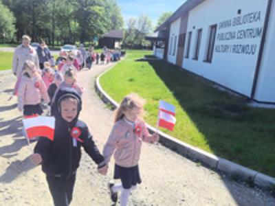 Grupa dzieci i nauczyciele idący w „Biało-czerwonym marszu”. Na zewnątrz.