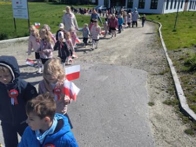 Grupa dzieci i nauczyciele idący w „Biało-czerwonym marszu”. Na zewnątrz.