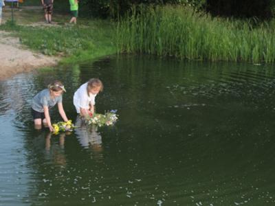 dwie dziewczynki  stojące w wodzie i puszczające wianki