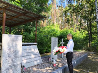 Mogiła zbiorowa żołnierzy Wojska Polskiego, drzewa, kwiaty, znicze.