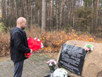 Zdjęcie przestawia mogiłę zbiorową, usytuowaną w lesie.