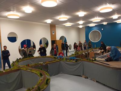 Grupa ludzi oglądająca makietę z kolejkami. Wewnątrz