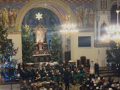 Nawa kościoła z ludźmi zasiadającymi w ławkach. Wewnątrz.