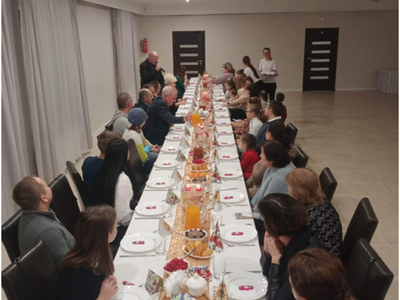 grupa osób siedzących przy stole – wewnątrz budynku