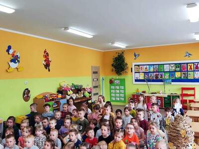 Grupa przedszkolaków słuchająca wykładu pszczelarza. Wewnątrz.