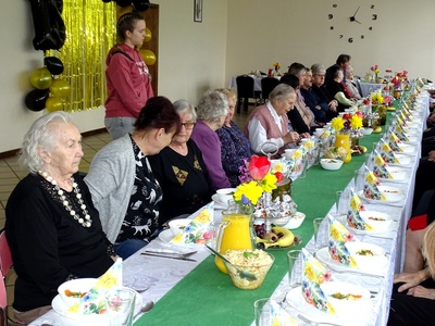 Seniorzy przy zastawionym stole. Wewnątrz.