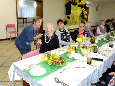 Seniorzy przy zastawionym stole. Wewnątrz.