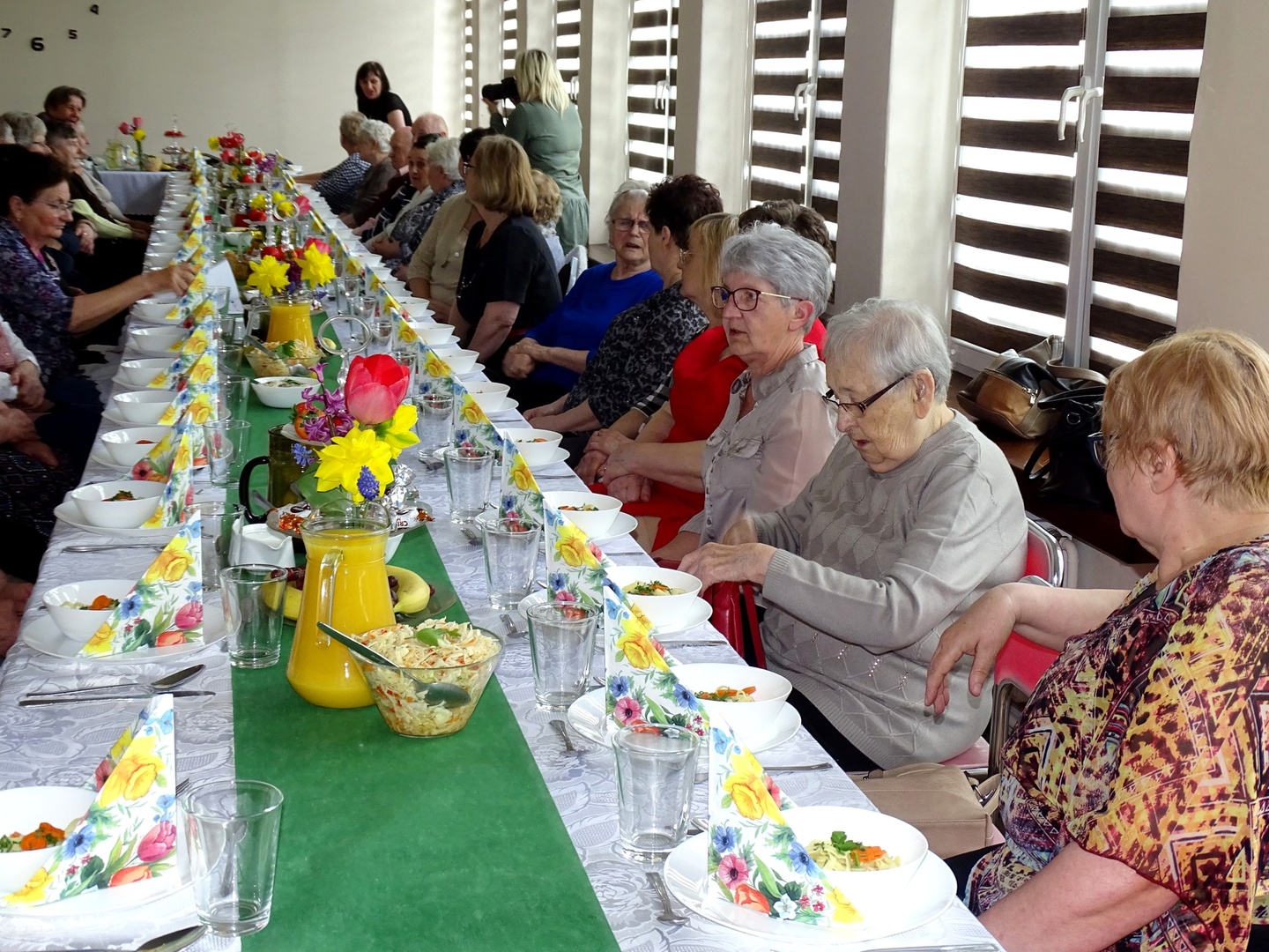 Seniorzy przy zastawionym stole. Wewnątrz.