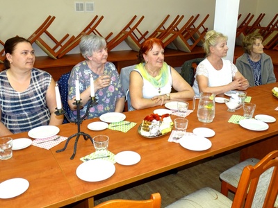Grupa kobiet siedząca przy zastawionym stole podczas wykładu. Wewnątrz.