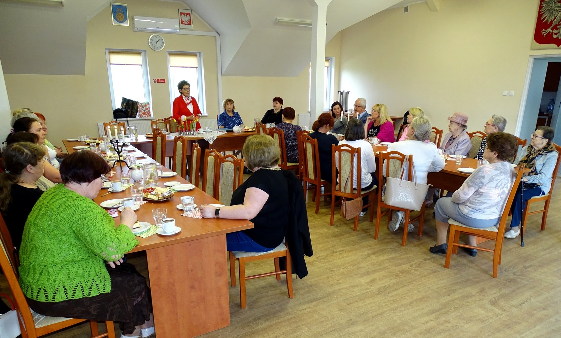 Grupa kobiet siedząca przy zastawionym stole podczas wykładu. Wewnątrz.