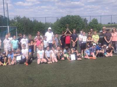 Grupa dzieci i dorośli na boisku sportowym. Na zewnątrz.