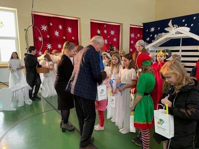 wewnątrz, wicestarosta ze współpracownikiem wręcza upominki występującym dzieciom