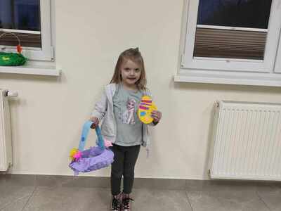 na zdjęciu widoczna dziewczynka trzymająca w ręku koszyk wielkanocny własnoręcznie wykonany na zajęciach. Zdjęcie wykonane wewnątrz pomieszczenia