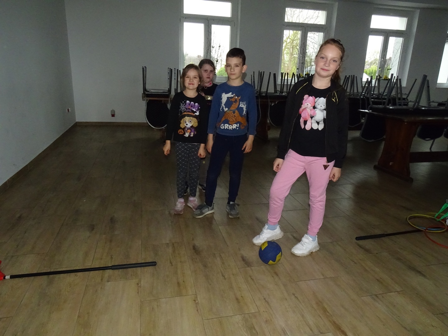 Grupa dzieci, które czekają na swoją kolejkę toczenia piłki do kręgli. Wewnątrz.