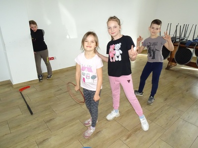 Dziewczynka biorąca udział w kolejnej zabawie sportowej – „Zbieranie piłeczek za pomocą specjalnego chwytaka”. Wewnątrz.
