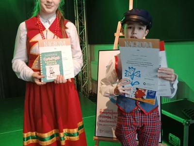 Dwójka dzieci trzymająca dyplomy. Wewnątrz.