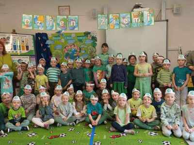Grupa przedszkolaków z trzema paniami opiekunkami ubrana na zielono. Wewnątrz.