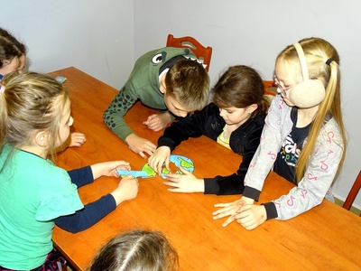 Grupa dzieci układa puzzle, z których powstanie kontur kuli ziemskiej. Wewnątrz.