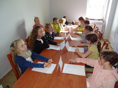 Grupa dzieci rozwiązująca zadania podczas konkursu. Wewnątrz.