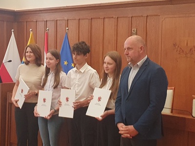 Marszałek, młodzież i nauczycielka pozują do zdjęcia. Wewnątrz.