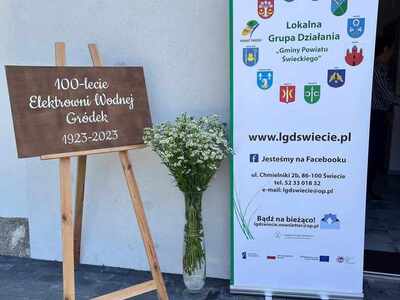 na zdjęciu widoczny rollaup i tablica informacyjna stojące na tle budynku. Zdjęcie wykonane na zewnątrz pomieszczenia