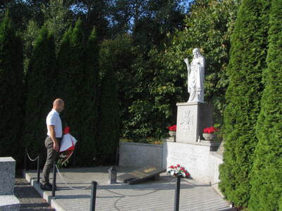 Mogiła zbiorowa żołnierzy Wojska Polskiego, drzewa, kwiaty, znicze.