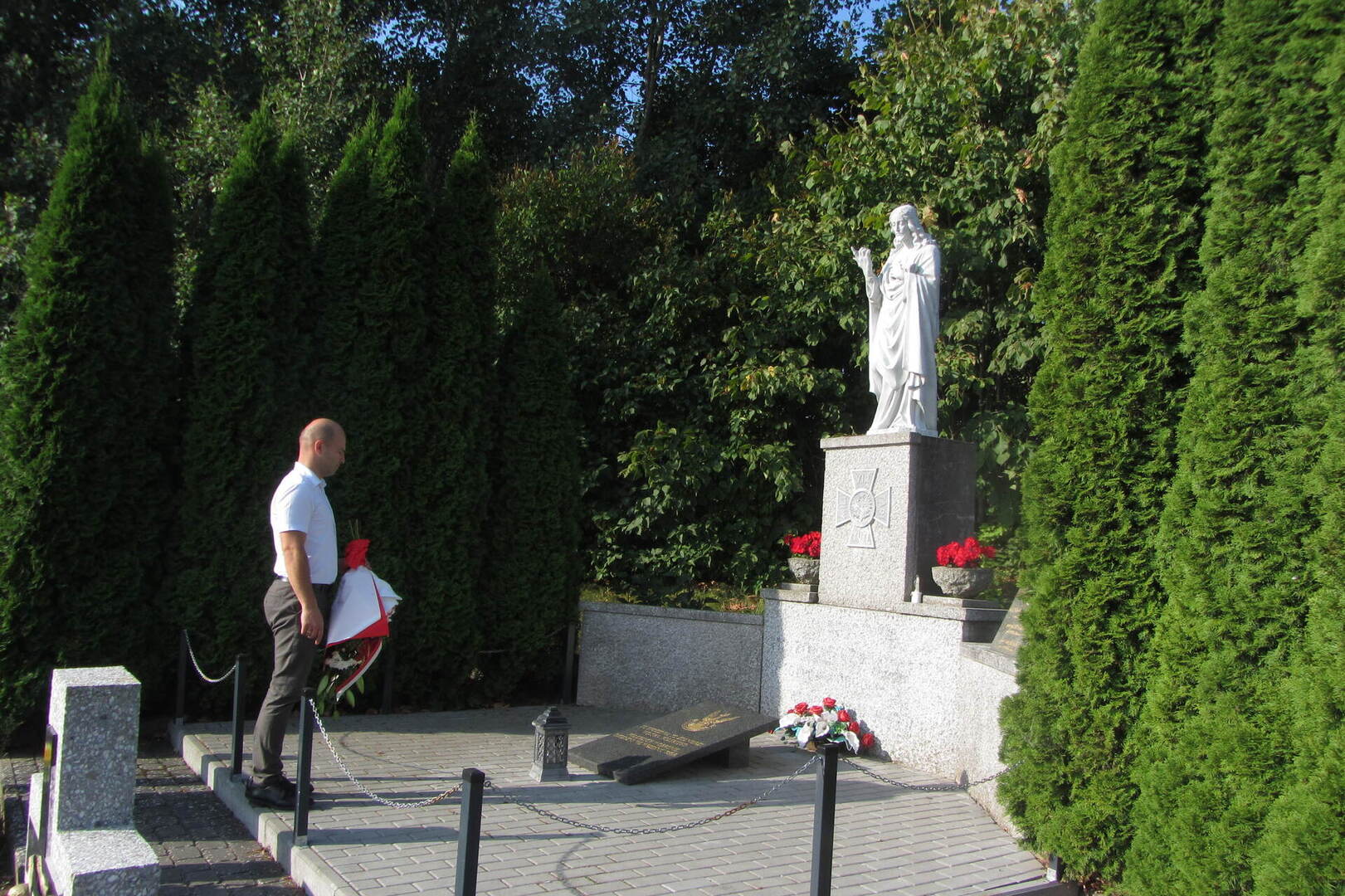 Mogiła zbiorowa żołnierzy Wojska Polskiego, drzewa, kwiaty, znicze.