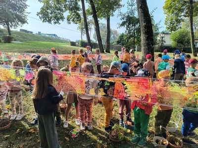 Grupa dzieci malująca farbami. Na zewnątrz.