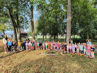 Grupa dzieci z opiekunami pozująca do zdjęcia. Na zewnątrz.