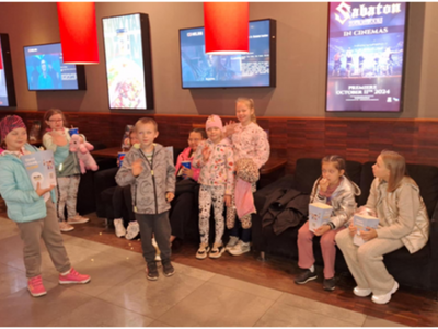 Wewnątrz, grupka dzieci czekających na wejście do sali kinowej.