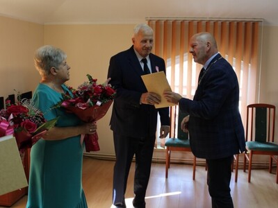 Wewnątrz. Cztery osoby stoją. jedna wręcza dyplom drugiej.