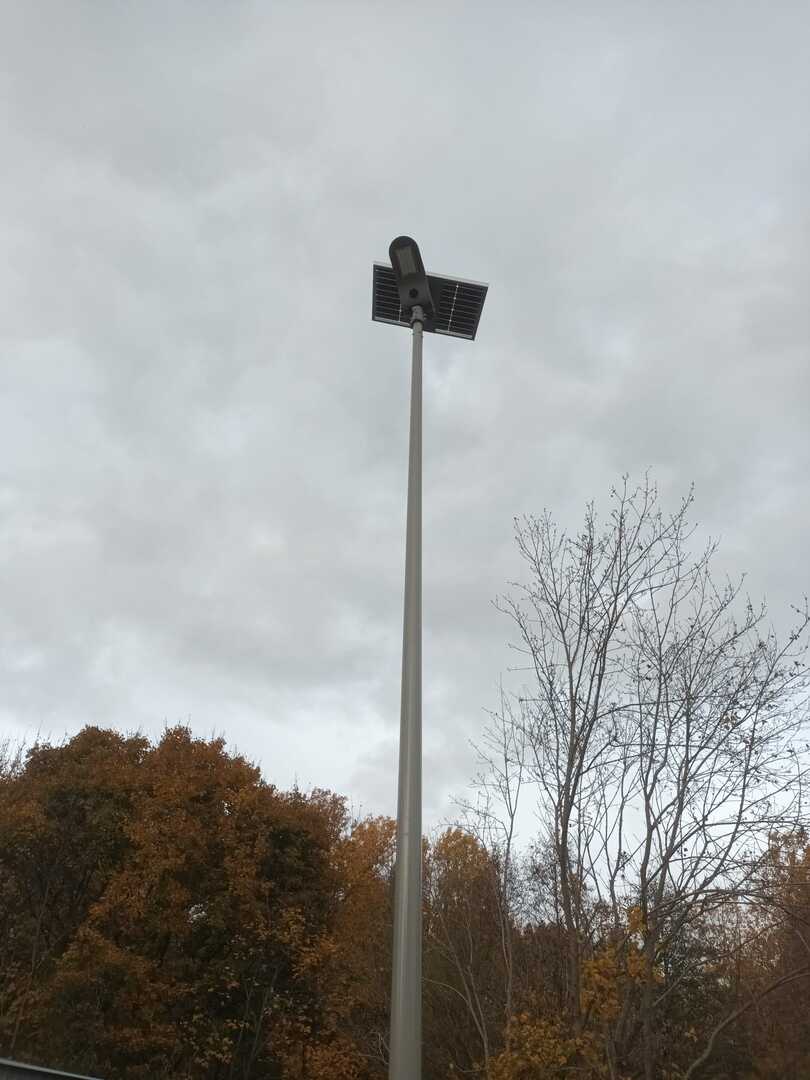 Lampa solarna na tle zachmurzonego nieba w oddali drzewa. Na zewnątrz.