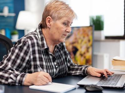 ZUS - kobieta zapisująca w notatniku oraz przeglądająca informacje w laptopie