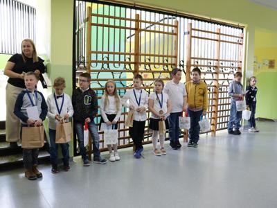 na zdjęciu w rzędzie stoją dzieci trzymające nagrody