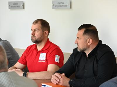 członkowie zespółów siedzą przy stole w sali konferencyjnej - trwają obrady