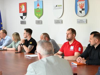 członkowie zespółów siedzą przy stole w sali konferencyjnej - trwają obrady