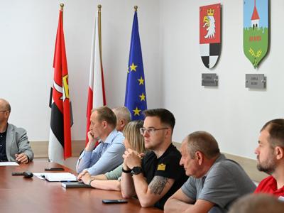 członkowie zespółów siedzą przy stole w sali konferencyjnej - trwają obrady