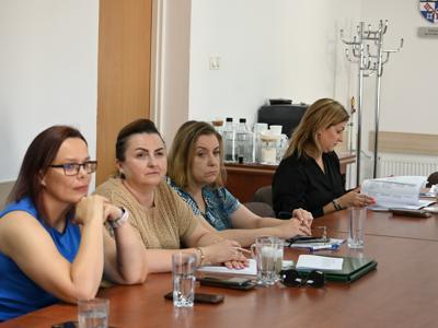 na zdjęciu uczestnicy spotkania, cztery panie siedzą przy stole w sali konferencyjnej, słuchają przemówienia