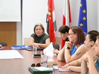 na zdjęciu uczestnicy spotkania, panie siedzą przy stole w sali konferencyjnej, słuchają przemówienia