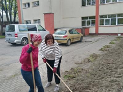 diwe kobiety podczas prac ogrodniczych w tle budynek szkoły