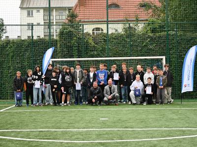 Zdjęcie grupowe wszystkich uczestników wraz z wicestarostą oraz trenerem w tle bramka, drzewa