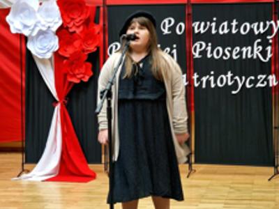 na zdjęciu dziecko stojące na scenie przy mikrofonie