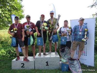 Zdjęcie zawodników na podium. W rękach trzymają nagrody.