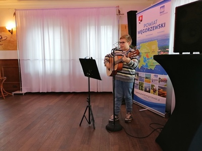 chłopiec gra na gitarze i śpiewa