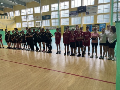 Zawodnicy w hali sportowej stoją w szeregu na rozpoczęciu zawodów
