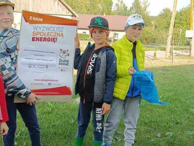 na zdjęciu uczestnicy projektu, chłopcy trzymają w ręku plakat informujący o projekcie